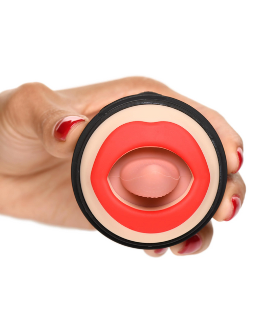A hand with red nail polish is holding a small, circular novelty item designed to look like lips with a tongue sticking out. The lips are red and the tongue is pink, all enclosed in a black circular frame. This XR Brands Lady Licker Rotating Tongue Stimulator with Discreet Case is also waterproof, ideal for adventurous clitoral orgasms.