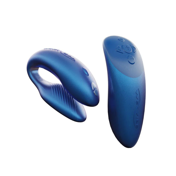 The We-Vibe Chorus Remote & App Controlled Couples' Vibrator in blue, by We-Vibe, is pictured alongside its matching remote control. The sleek and curved design features ribbed detailing on one end. With touch-sensitive vibrations and adjustable settings controlled by the remote, it promises an exciting experience for couples.