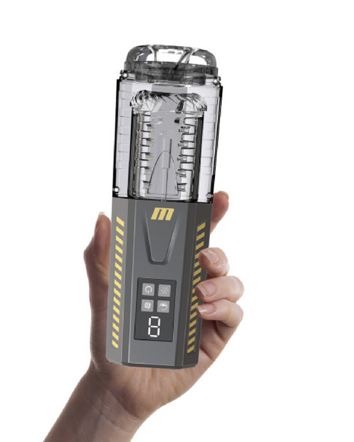 A hand holds a grey portable device with a transparent top section and an electronic display screen on the front. The device features yellow striped accents and a symmetric, cylindrical design. Equipped with an automatic stroker, the central display shows several buttons and an LED screen. This is the Spin Master Pro Vibrating, Stroking, Rotating, Automatic Stroker by Blush.