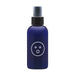 A dark blue spray bottle with a black cap and nozzle is shown against a white background. The label on the bottle features a simple white face-like design with two small circles for eyes and a larger circle for the mouth, indicating its soothing Aloe and Green Tea Extract formula. This is the Alu Aloe Vera Water Based Lubricant and Intimate Moisturizer, 4 oz by Dame Products.