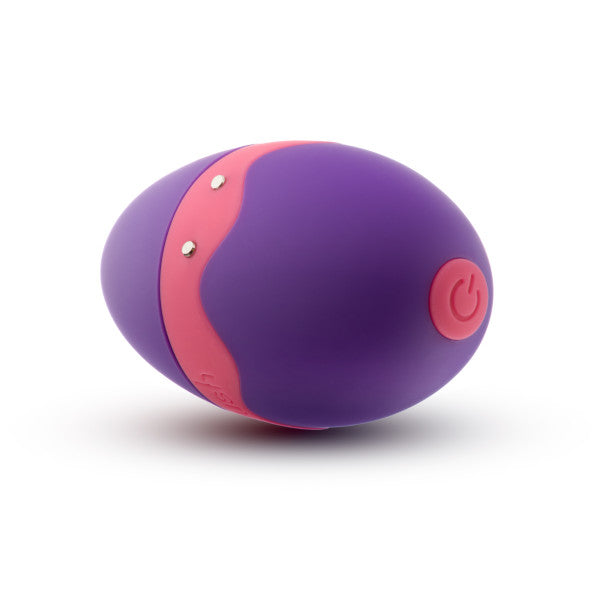 The Aria Flutter Tongue Clitoral Licking Oral Sex Vibrator by Blush is a purple, egg-shaped electronic device adorned with a pink wave design in the middle. It includes a power button and metal contacts on its body, indicating it is a type of personal gadget. Featuring 7 vibration modes, this device offers an array of stimulating experiences.