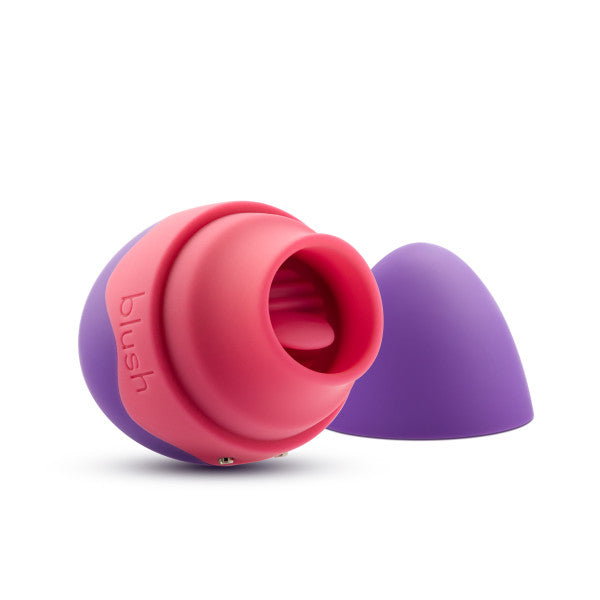 The Aria Flutter Tongue Clitoral Licking Oral Sex Vibrator by Blush is a small, colorful silicone personal massager with a pink and purple color scheme. The device has a rounded shape with an open end and includes a removable purple cap. Featuring 7 vibration modes, the word "blush" is embossed on the pink part of the massager.