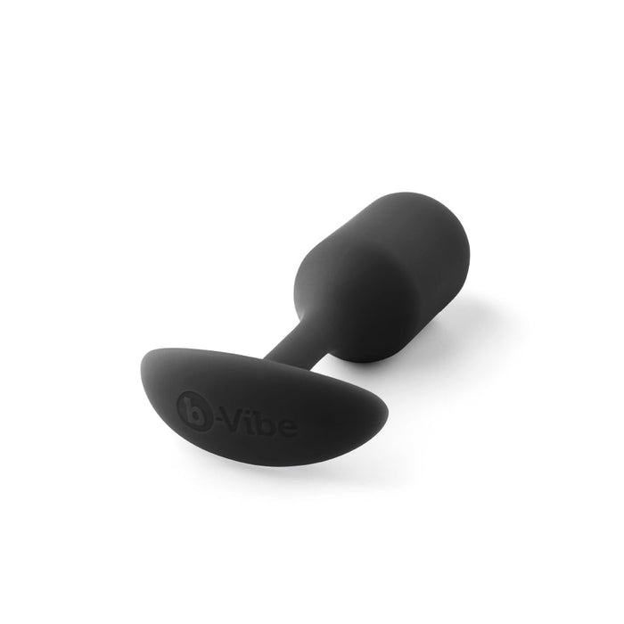 The B-vibe Snug Plug 2 is a black, cylindrical silicone anal plug featuring a tapered base and the "b-Vibe" branding on the flat end. Weighing 5 oz, this weighted plug has a smooth texture, making it a premium silicone anal toy designed for personal use.