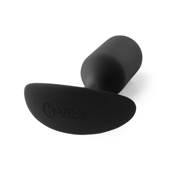 The B-vibe Snug Plug 3 Weighted Silicone Butt Plug - 6 oz, available in various colors, is a black, cylindrical plug featuring a smooth, minimalist design. It has a flared base for safe removal with the "b-Vibe" brand name embossed on it. Additionally, this plug is completely waterproof.