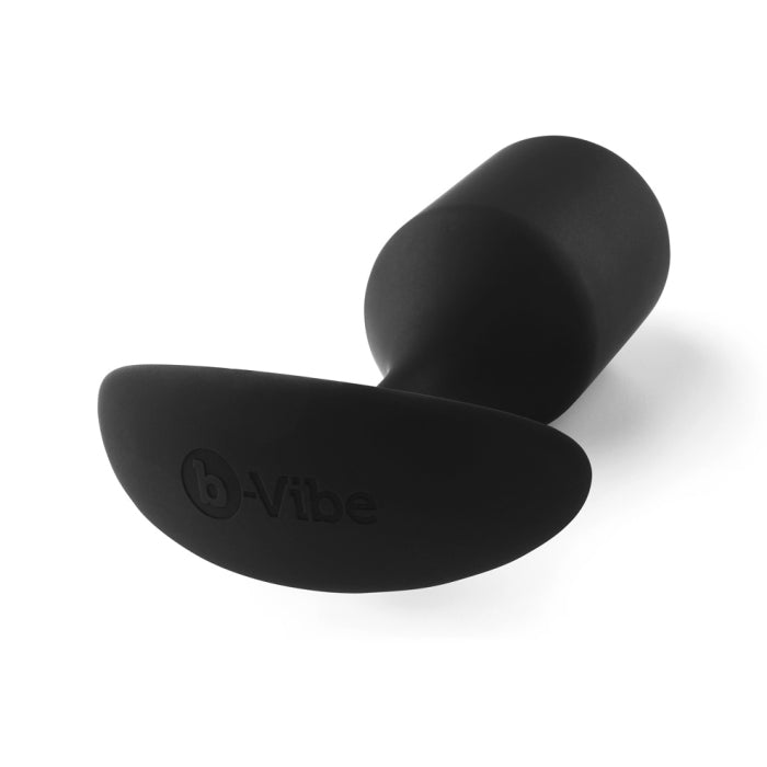 A black B-vibe Snug Plug 4 XL Weighted Silicone Butt Plug (9 oz) featuring a smooth, curved surface and a wide base. Designed for enhanced anal play, the product is displayed against a plain white background, clearly showing the brand name "b-Vibe" embossed on the base.