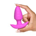 A hand with manicured nails holds the BANG! Rotating & Vibrating Silicone Butt Plug with Remote by XR Brands. This small, pink butt plug features a flared base and is crafted from silky smooth silicone, with a bulbous shape that tapers to a rounded tip.