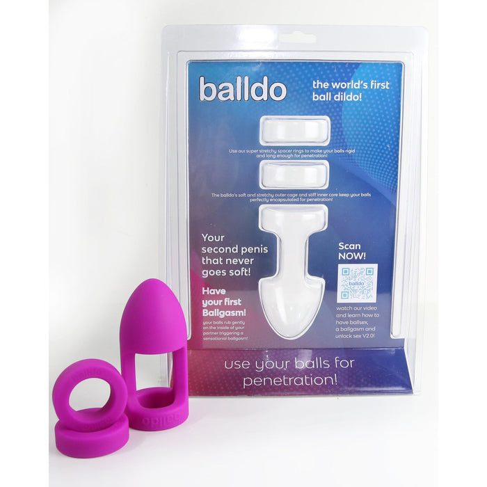 The product packaging for Balldo: The World's First Ball Dildo - Purple by Balldo showcases a white device along with detailed instructions. Prominently displayed in the foreground is a purple silicone accessory featuring rings, engineered specifically for testicle penetration using the Balldo, and ensuring an unprecedented ball orgasm experience.