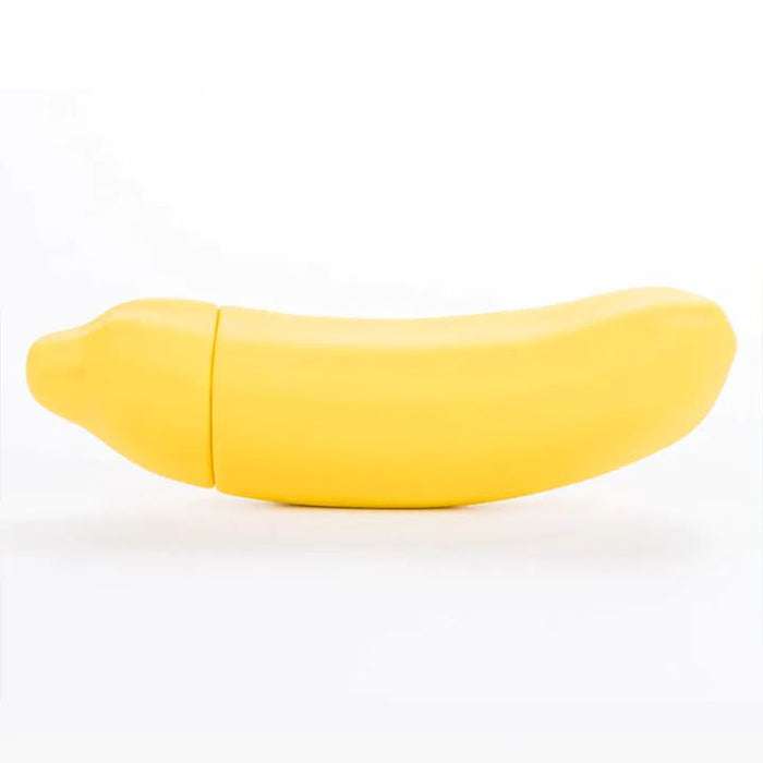 A yellow, banana-shaped plastic container from Dame Products sits against a white background. The Banana Emojibator Ultra Discreet First Time Bullet Vibrator is waterproof and has a smooth texture, appearing to open in the middle to resemble a real banana. This high-quality silicone toy features 10 vibration patterns for added fun.