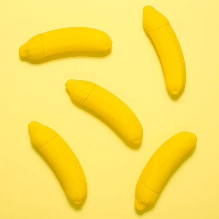 Five Banana Emojibator Ultra Discreet First Time Bullet Vibrators from Dame Products, each banana-shaped with yellow caps, are arranged on a yellow background. These waterproof toys, featuring 10 vibration patterns, are positioned at various angles, creating a playful and vibrant composition.