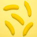 Five Banana Emojibator Ultra Discreet First Time Bullet Vibrators from Dame Products, each banana-shaped with yellow caps, are arranged on a yellow background. These waterproof toys, featuring 10 vibration patterns, are positioned at various angles, creating a playful and vibrant composition.