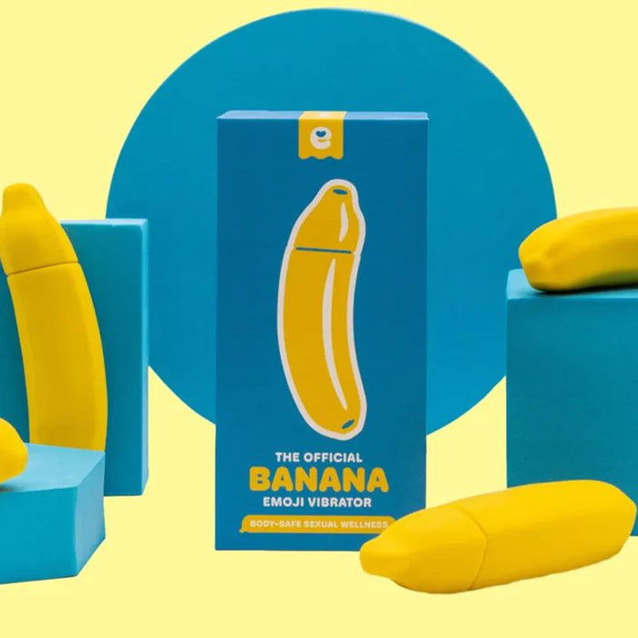 A product display featuring the "Banana Emojibator Ultra Discreet First Time Bullet Vibrator" by Dame Products in bright yellow and blue packaging. The box depicts a banana shape in the center and is surrounded by three banana-shaped, silicone vibrators on differently sized blue platforms, boasting 10 vibration patterns for endless fun.