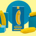 A product display featuring the "Banana Emojibator Ultra Discreet First Time Bullet Vibrator" by Dame Products in bright yellow and blue packaging. The box depicts a banana shape in the center and is surrounded by three banana-shaped, silicone vibrators on differently sized blue platforms, boasting 10 vibration patterns for endless fun.