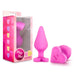 The Blush Be Mine Naughty Candy Heart Butt Plug - Pink is a perfect choice for anal beginners. This pink silicone butt plug set features adorable heart-shaped bases with "BE MINE" written on them. The set is displayed outside its pink-themed retail packaging, which showcases heart-shaped graphics and the playful text "Play with Me! NAUGHTY CANDY HEARTS.