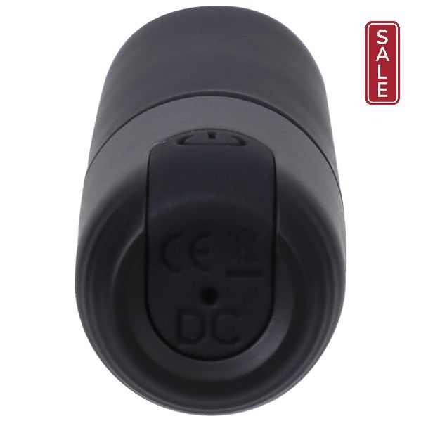 An up-close shot of the Beginner Classic Black Silicone Bullet Vibrator In a Bag by Doc Johnson, shaped like classic lipstick and USB rechargeable, viewed from the base. The base features a small round button labeled "DC" along with CE certification symbols and disposal instructions. The device boasts a smooth matte finish.