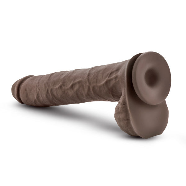 The Blush Big Daddy 14 Inch Dual Density Suction Cup Dildo in Chocolate, featuring a realistic and large design with a detailed shaft and flexible spine, lies on a white background.