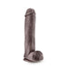 The Big John 11.5 Inch Dual Density Suction Cup Dildo - Chocolate by Blush features a realistic design with a veiny texture, detailed head, and attached testicles, all standing upright on a strong suction cup base.