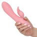 Person holding the CalExotics California Dreaming Pasadena Player G-Spot Rabbit Vibrator, a pink silicone sex toy featuring a textured, slightly curved shaft and a separate clitoral stimulator. The rabbit vibe boasts a soft finish with buttons visible on its side, designed for intimate use.