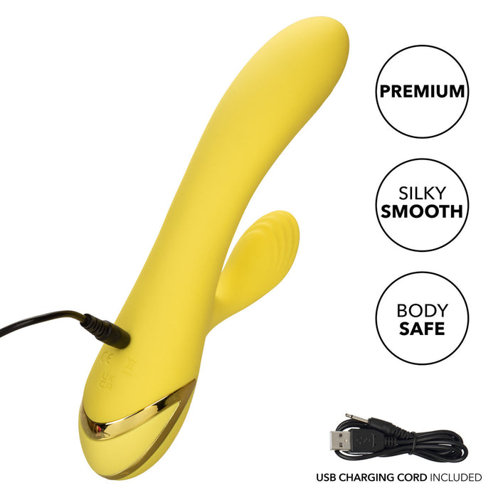 The California Dreaming San Diego Seduction G-Spot Thumping Rabbit Vibrator by CalExotics is a yellow, curved personal massager with a smaller contoured section designed for clitoral stimulation. It features a USB charging cord plugged in at the base and comes with labels indicating it is "Premium," "Silky Smooth," and "Body Safe." The USB charging cord is also shown separately in the lower part of the image.