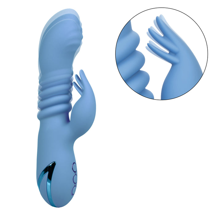 The California Dreaming Santa Cruz Coaster Thrusting G-Spot Rabbit Vibrator by CalExotics, a light blue silicone sex toy, features a curved, ribbed shaft and a clitoral stimulator resembling rabbit ears. The image includes a circular close-up inset of the clitoral stimulator, highlighting its texture and detail. This waterproof vibrator offers unparalleled clitoral stimulation for ultimate pleasure.