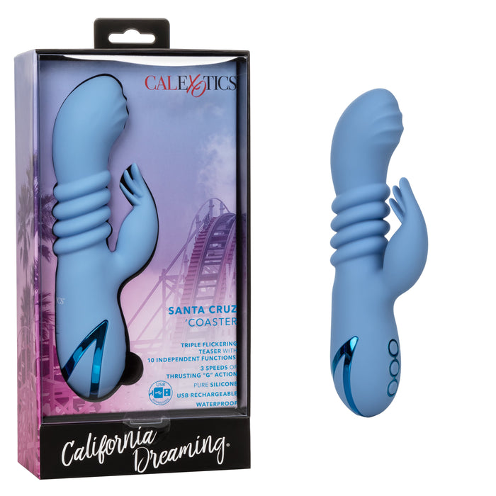 A light blue California Dreaming Santa Cruz Coaster Thrusting G-Spot Rabbit Vibrator, designed for dual stimulation with ridges and a curved tip, is displayed beside its packaging. The box is branded "CalExotics" and "California Dreaming," featuring a roller coaster image. This waterproof product includes clitoral stimulation features.