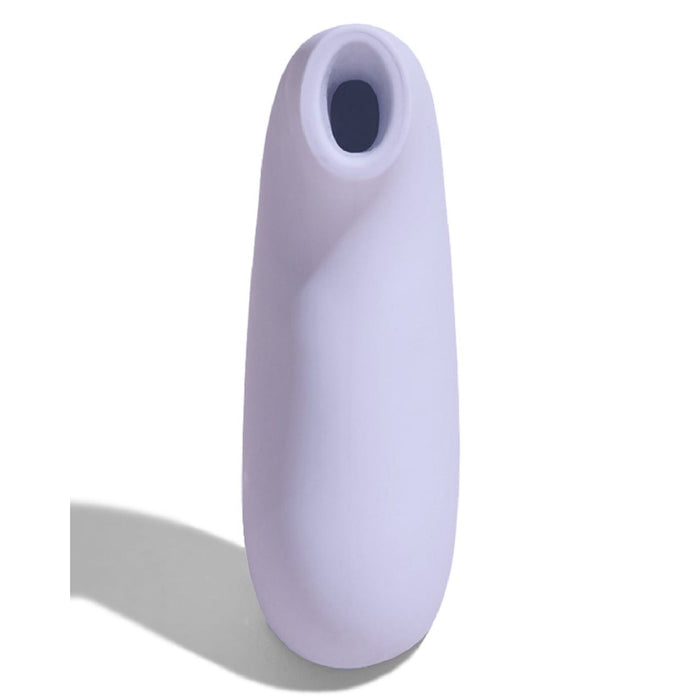 A Dame Aer Clitoral Pressure Wave Vibrator by Dame Products in purple, features a cylindrical shape with a rounded tip and a small, circular opening at the top. Utilizing air pulsation technology for clitoral stimulation, it casts a shadow to the left against a white background.