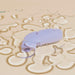 A small, purple Dame Aer Clitoral Pressure Wave Vibrator from Dame Products lies on a beige surface, surrounded by clear, circular puddles of water. The reflections create a distorted ripple effect around the device, hinting at its air pulsation technology that enhances intimate moments.