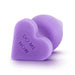 The Do Me Now Naughty Candy Heart Purple Butt Plug by Blush is heart-shaped with a slightly bulbous, rounded end and the words "DO ME NOW" etched onto its silicone surface. Positioned on a white background and slightly tilted to the side, it is ideal for anal beginners.