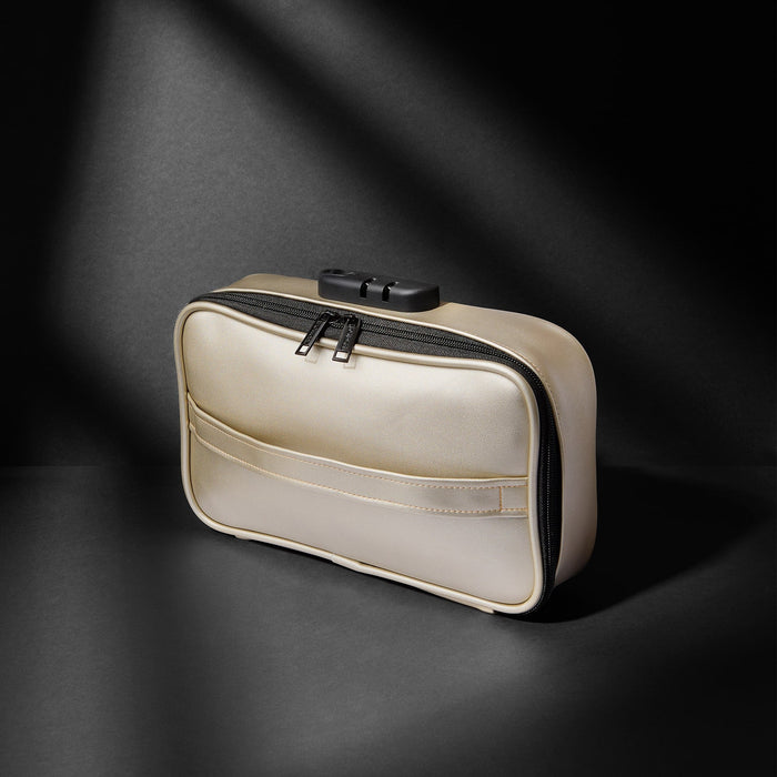 The Lovely Planet Dorcel Lockable Discreet Gold Storage Box sits in soft lighting against a dark background. The box features a front pocket and boasts a sleek, minimalist design that’s perfect for discreet storage of personal items, including sex toys. Shadows and lighting create a dramatic effect.