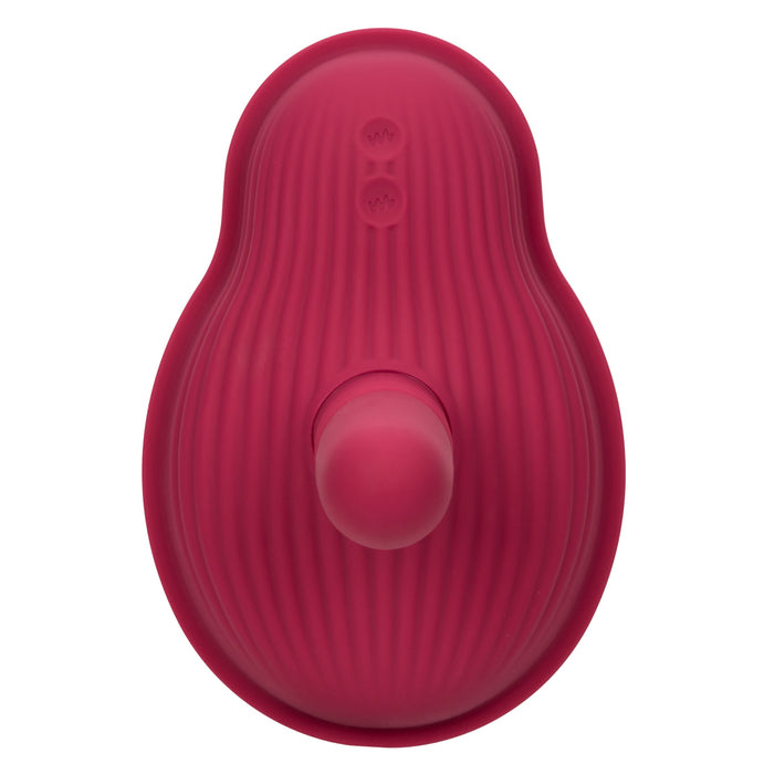 Introducing the CalExotics Dual Rider Remote Control Thrust & Grind Humping Vibrator: A pink, oval-shaped silicone personal massager with textured ridges. This waterproof massager features a protruding cylindrical nub and two small control buttons on its surface.