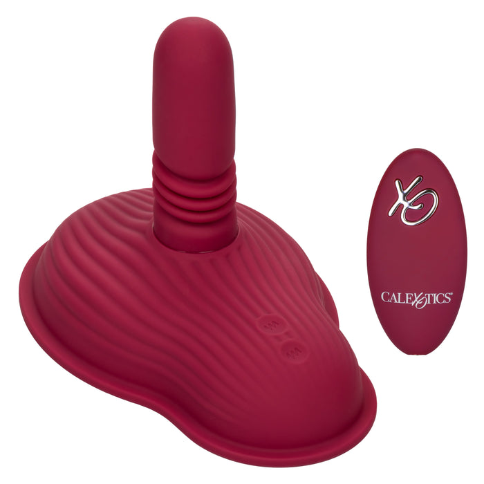 The Dual Rider Remote Control Thrust & Grind Humping Vibrator by CalExotics features a maroon-colored, elongated vibrator with a ribbed base, paired with a matching maroon remote control massager. The remote control includes clearly labeled "CalExotics" buttons and an "XO" logo on its surface. This waterproof massager showcases a ribbed texture and smooth finish, ideal for versatile play.
