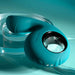 The Thumbs Up Shallow Penetration Vibrator with Finger Loop in teal silicone features a circular attachment and ribbed texture, set against a turquoise backdrop. Visible buttons highlight its electronic vibrating function.