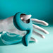 The teal Thumbs Up Shallow Penetration Vibrator, featuring a finger loop and curved end, is showcased resting on a white mannequin hand against a turquoise background.