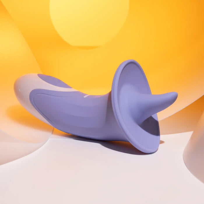 An Evolved Novelties Lix & Kisses Swirling Tongue Oral Sex Vibrator, boasting a modern and sleek design with its purple and white conical shape and flared base, rests on a white surface. Crafted from phthalate-free silicone, it exudes quality. The background features a gradient of yellow hues, creating a warm and vibrant atmosphere.