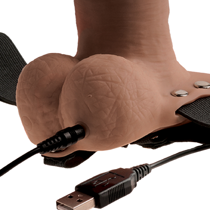 A detailed view of the Fetish Fantasy Vibrating 6 Inch Hollow Dildo in caramel shows realistic veins and texture. It features a USB cable, black straps, metallic buttons on the side, and visible cables in the foreground.