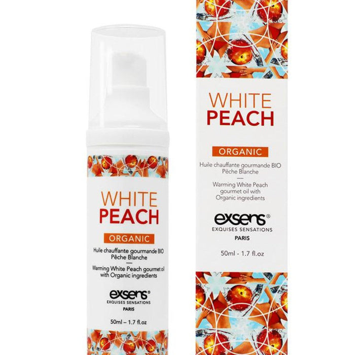 A bottle of Exsens Organic White Peach Flavored Warming Massage Oil next to its packaging. The packaging features vibrant orange peaches and white flowers, emphasizing its natural ingredients.