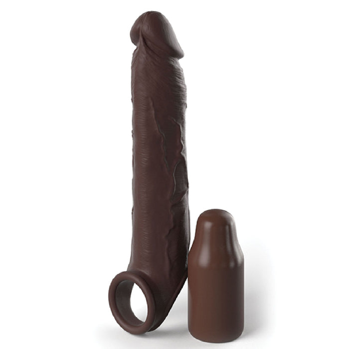 The Fantasy 7 Inch Silicone Penis Extension with Ball Strap - Chocolate by Pipedream Products stands upright next to a smaller, rounded cylindrical object of the same color. The larger object, which includes a ring at its base, is ultra-realistic and both items are made from silicone, designed to serve as an erectile dysfunction aid.