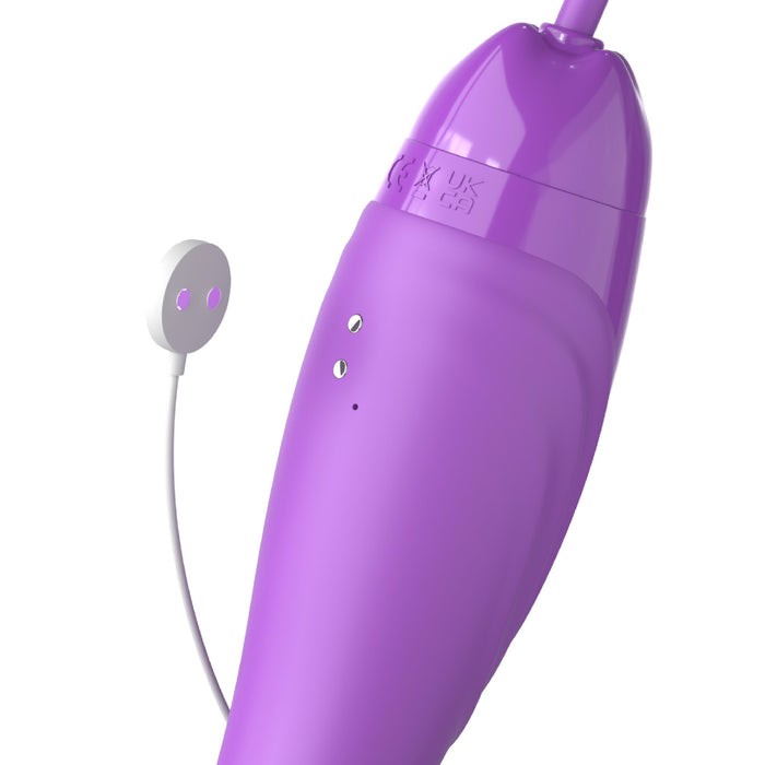 A close-up of the Fantasy For Her Ultimate Pleasure Max Licking Sucking Vibrator by Pipedream Products, featuring a sleek purple design with a smooth surface. It has two small metal contact points on one side and includes a white cord attached to a white circular component with two small holes, reminiscent of the design of a double-ended vibrator.