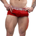 A man wearing bright red boxer briefs with the waistband text "Perfect Fit Brand" holds the waistband with both hands. The photo focuses on his lower torso, highlighting his muscular arms, tattoo, and legs. The background is plain white, giving an ultra-real feeling to the SilaSkin™ fabric of the Fat Boy Ultra Fat 5.5 Inch Penis Girth Extender Sleeve with Ball Strap.