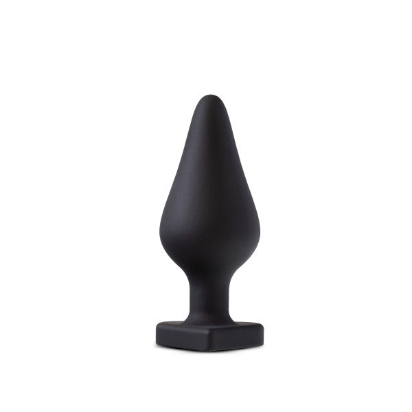 The Fuck Me Silicone Heart Butt Plug - Black by Blush features a black, matte-finished silicone design with a tapered, conical top and a heart-shaped base. Its shape resembles a tree or Christmas tree, offering both simplicity and elegance in its appearance.