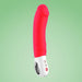 The Fun Factory Big Boss Thick Vibrator in pink, designed for G-spot stimulation, features a large, curved shape and a white handle with intuitive controls and buttons. It is presented against a light green background.