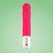 An elongated, large pink vibrator with a realistic phallic shape, the "Fun Factory Big Boss Thick Vibrator" by Fun Factory, stands vertically against a green gradient background. Its white base features control buttons and offers ideal g-spot stimulation while being waterproof for versatile use.