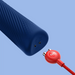 Image shows a close-up of the Fun Factory Vim Silicone Weighted Rumbly Wand Vibrator in dark blue, featuring a small circular port near its base. A red, branded Fun Factory cable with two prongs is positioned near the port, indicating potential connection or charging. The device's powerful wand design hints at delivering deep vibrations for optimal use. The background is a solid light blue.