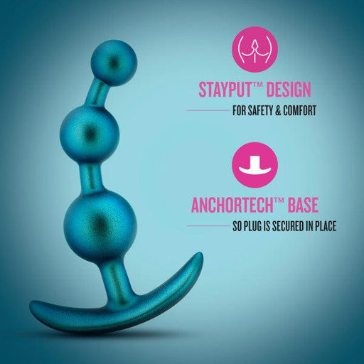 Displayed is the Gamma Silicone Anal Beads & Butt Plug by Blush in a blue silicone material featuring a beaded design. The text highlights its "STAYPUT™ Design for Safety & Comfort" and "ANCHORTECH™ Base so Plug is Secured in Place," focusing on its safety and security features. Discover prostate pleasure with this innovative anal toy.