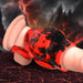 A close-up image of a character's lower half wearing red and black pants, lying on a cracked, lava-strewn ground. Jagged mountains and a stormy sky with lightning dominate the background, creating a dramatic and intense scene. The Hell Hound Canine Knot Girth Enhancer with Ball Strap by XR Brands is barely noticeable beneath the fabric, adding to the tension.