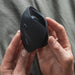 A close-up of hands holding a modern black ergonomic vertical mouse with Hot Octopuss Pulse Solo Essential Oscillating Penis Masturbator Technology over a grey textured background.