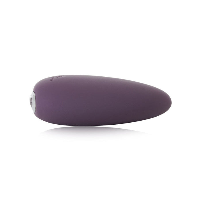 A small, sleek, egg-shaped device with a matte purple finish and a silver button on one end. The Je Joue Mimi Clitoral and External Vibrator - Purple is displayed against a plain white background, showcasing its modern and minimalist design perfect for clitoral stimulation.