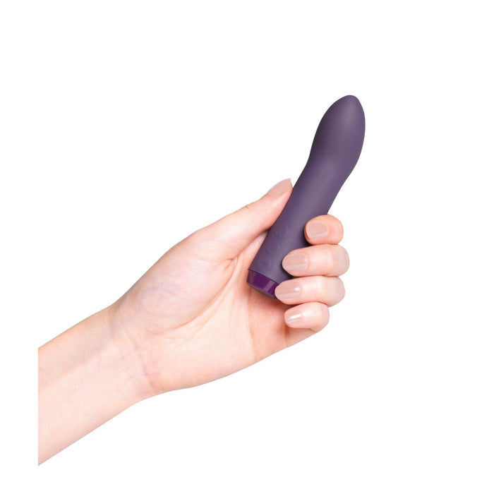 A hand holding the Je Joue Powerful Internal or External Bullet - Purple, a small vibrator from Je Joue, featuring premium silicone with a smooth surface and a slightly rounded tip, set against a plain white background.