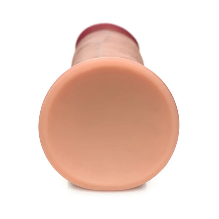 A close-up image of the flat base of the Jock Dual Density Silicone Thick 7 Inch Dildo with Suction Cup - Vanilla from XR Brands, showcasing its cylindrical, flesh-toned appearance with a conical shape. The material appears smooth and solid, featuring a wider base that tapers as it extends upwards. This dildo is also strap-on harness compatible for versatile use.