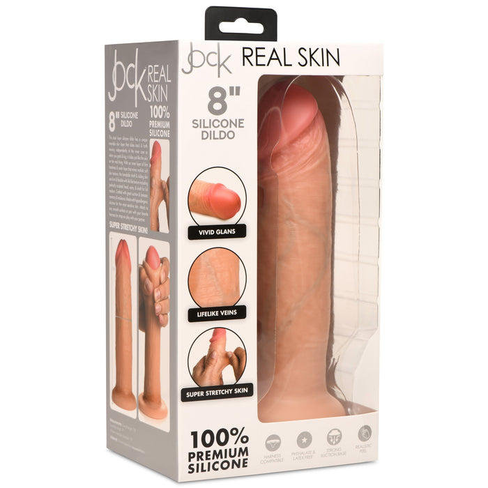 Box packaging of a sex toy labeled as "Jock Real Skin 8 Inch Silicone Suction Cup Dildo - Vanilla" by XR Brands. The package highlights features such as vivid glans, lifelike veins, and super stretchy skin. With dual density for a more realistic feel, it’s made from 100% premium silicone. The dildo's tip is visible through the clear plastic window.