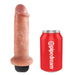 A vanilla-colored squirting dildo with a black base stands upright next to a red soda can labeled "Pipedream." This ultra-realistic 6-inch hand-sculpted King Cock dildo by Pipedream Products is notably taller than the can, emphasizing its impressive size and craftsmanship.